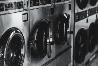 Black and white image of industrial washing machines in a retro style laundry facility.